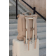 Sac à dos beige posé sur une valise rigide claire devant un escalier en pierre, maintenu par sa bande arrière autour de la poign