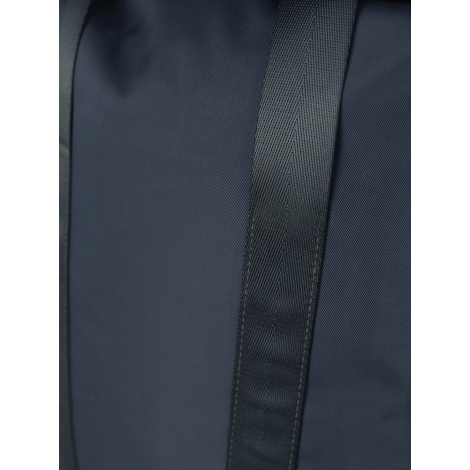 Gros plan sur une sangle bleu marine à tissage serré, cousue verticalement sur le tissu lisse d'un sac de week-end, avec un renf