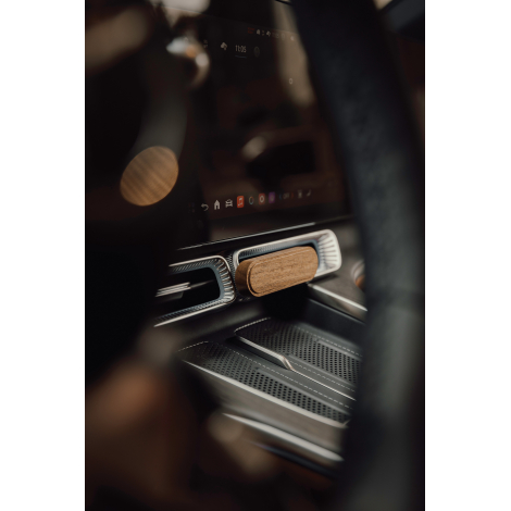 Diffuseur de parfum en bois d'acacia installé sur une grille d'aération horizontale sous l'écran central d'une voiture, dans un 
