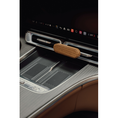 Vue rapprochée du diffuseur de parfum en bois d'acacia fixé sur une grille d'aération horizontale, sous l'écran de commande d'un