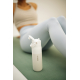 Gourde filtrante blanche posée sur un tapis de sport vert, avec capuchon ouvert et embout de boisson apparent. Une femme en tenu Gourde filtrante blanche posée sur un tapis de sport vert, avec capuchon ouvert et embout de boisson apparent. Une femme en tenu