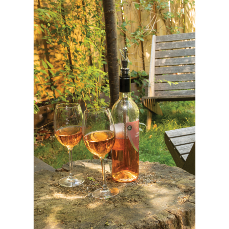 Bouteille de vin rosé équipée d'une tige rafraîchissante avec verseur transparent, posée sur une table en pierre aux côtés de de
