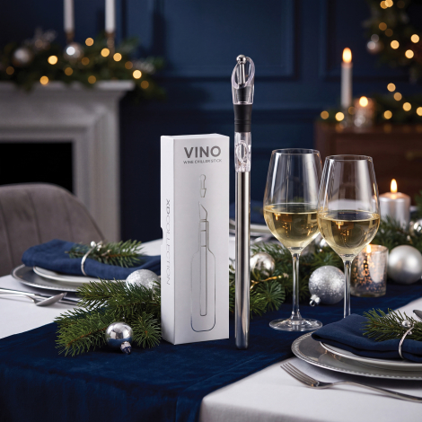 Tige rafraîchissante à vin argentée avec verseur transparent, présentée verticalement à côté de son coffret blanc et de deux ver