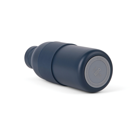 Bouteille isotherme bleu marine mate, couchée sur le côté, avec un large manchon central en silicone. Le dessous présente une ba
