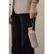 Gros plan sur une femme en blazer beige et pantalon noir, portant une bouteille isotherme beige clair par sa dragonne souple. Le