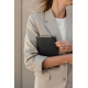 Femme vêtue d'un blazer beige tenant contre elle un carnet noir à couverture texturée, tout en maintenant un stylo bille noir à Femme vêtue d'un blazer beige tenant contre elle un carnet noir à couverture texturée, tout en maintenant un stylo bille noir à