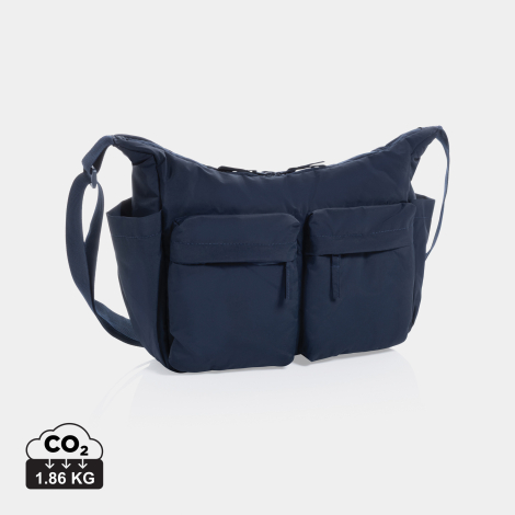 Vue de trois quarts d'un sac bandoulière bleu marine, avec deux poches avant à rabat munies de fermetures zippées, une poche lat