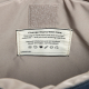 Gros plan sur l'intérieur beige d'un sac, montrant une étiquette rectangulaire cousue avec plusieurs lignes de texte et des pict