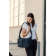 Une femme en t-shirt blanc et pantalon noir porte un sac bandoulière bleu marine à deux poches avant et poches latérales, tout e