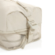 Gros plan sur un cube de rangement beige, montrant une fermeture zippée, une sangle de compression réglable avec boucle en plast