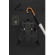 Sac à dos noir mat posé à plat sur un fond sombre, entouré d'un carnet avec montre, de lunettes et d'un parapluie à manche en bo