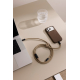 Câble de recharge beige partiellement enroulé sur une table, avec une attache assortie et un connecteur USB-C libre. Il relie un Câble de recharge beige partiellement enroulé sur une table, avec une attache assortie et un connecteur USB-C libre. Il relie un
