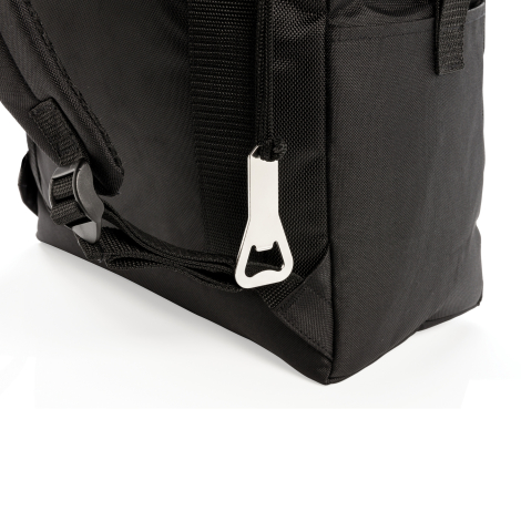 Gros plan sur l'angle inférieur du sac isotherme noir, avec décapsuleur métallique argenté suspendu à un cordon, sangle textile 