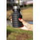 Bouteille pliable noire en silicone compactée, tenue dans une main en extérieur. Le corps présente plusieurs anneaux rapprochés,