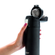 Une main tient un mug isotherme noir mat, donnant un aperçu de sa taille et de sa prise en main. Le pouce actionne le bouton arg
