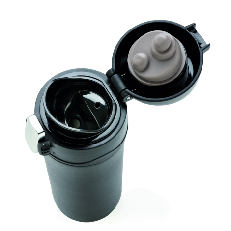 Gros plan en plongée sur le bouchon ouvert d'un mug isotherme noir, montrant l'intérieur du clapet avec deux embouts gris de tai